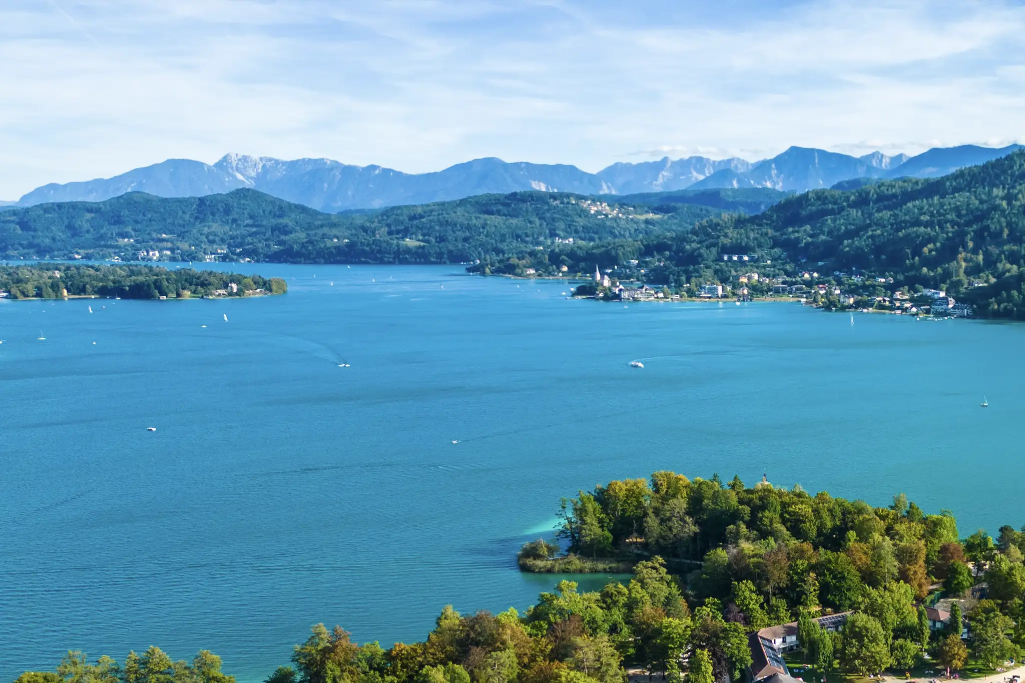 Urlaub am Wörthersee, Panorama des Sees, mit Bergen im Hintergrund und Maria Wörth