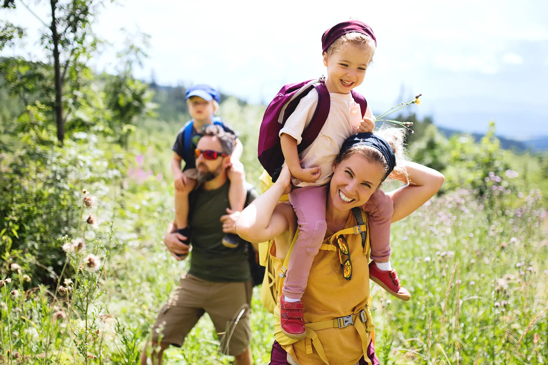 Familienurlaub Kärnten am Wörthersee, auf blühenden Wiesen unterwegs mit den Kindern auf den Schultern.